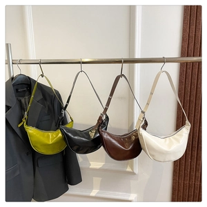 Row of four colorful faux leather crescent saddle bags hanging on a display rack