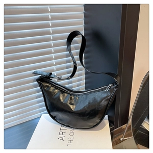Detailed view of a black glossy hobo bag with silver zipper on a white display box