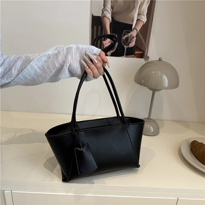 Minimalist black trapezoid handbag in matte faux leather with slim shoulder straps