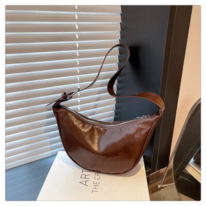 Detail of dark brown crescent saddle bag showing smooth glossy texture and zipper closure