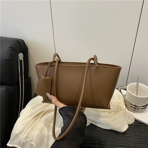 Minimalist dark brown trapezoid leather handbag with long straps and mini charm accessory