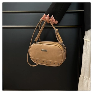 Detail of khaki leather crossbody bag featuring metallic rivets and a logo plaque