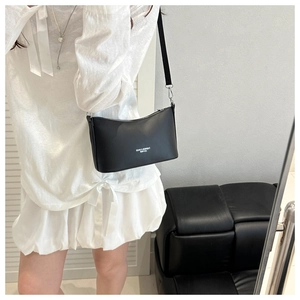 Detail of black leather shoulder bag showing fashion text print and adjustable strap on model
