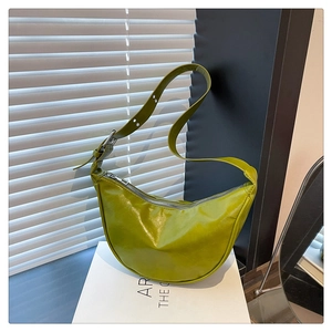 Detail of green crescent saddle bag showing glossy textured leather and silver zipper