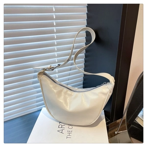 Detailed view of a white crescent hobo bag with glossy finish and adjustable strap
