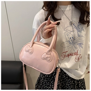 Close-up of pink shell-shaped crossbody bag with decorative 3D bows and shoulder strap
