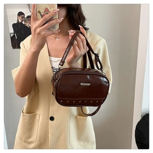 Detail of dark brown faux leather mini bag with silver studs and adjustable shoulder strap