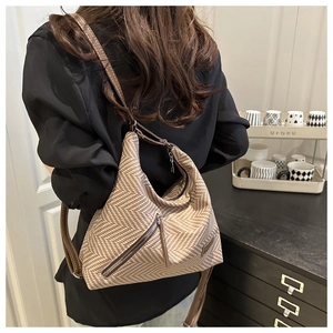 Detail of herringbone woven fabric texture and brown leather strap on hobo bag