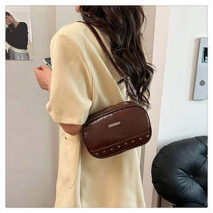 Detail of vintage brown leather crossbody bag with metal rivets and adjustable strap