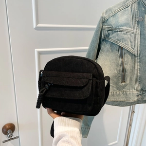 Minimalist black corduroy crossbody bag with woven puller and front pocket for women