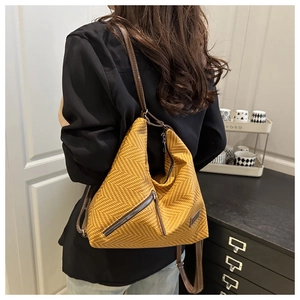 Détail du sac à dos tissé jaune avec garniture en cuir brun et poches zippées