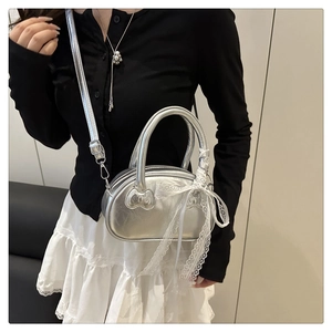 Detailed macro view of silver metallic shell bag featuring lace ribbon and cat ear stitching