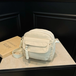 Minimalist beige corduroy crossbody bag with woven zipper pull and wide fabric strap