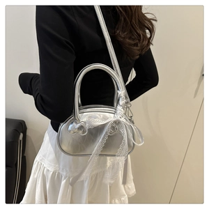 Close-up of silver shell bag with lace bow charm and metallic finish on model