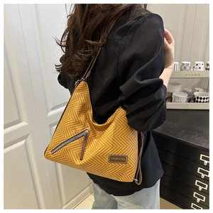 Gros plan d'un sac en paille jaune gingembre avec détail de fermeture éclair diagonale
