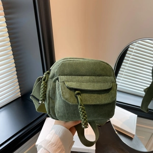 Green corduroy crossbody bag for women featuring a woven pendant and adjustable strap