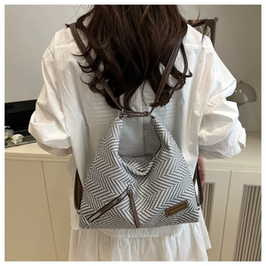 Détail du sac à bandoulière tissé avec sangle en cuir marron et étiquette de mode