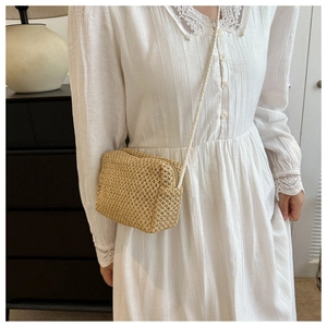 Detail of a handmade mini straw crossbody bag featuring woven texture and zipper closure