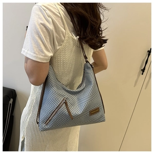 Détail du tissu tissé bleu et blanc avec finitions en cuir marron et logo de la sacoche