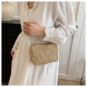 Close-up of handmade straw crossbody bag with white woven strap on model's lace dress