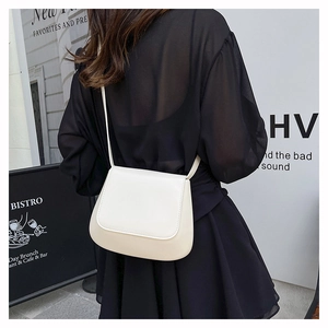 Chic cream beige saddle bag on model back view in a minimalist urban street cafe setting