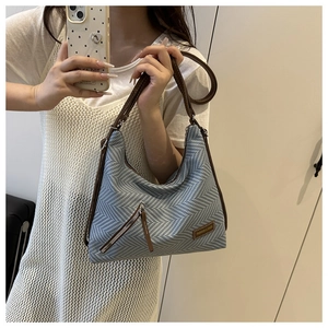 Détail du sac à bandoulière en paille tissée avec toile bleue et sangle en cuir