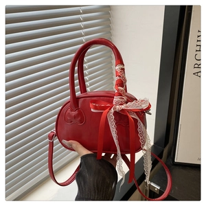 Detail of red glossy mini bowling bag featuring lace bow and kitty embossed handle