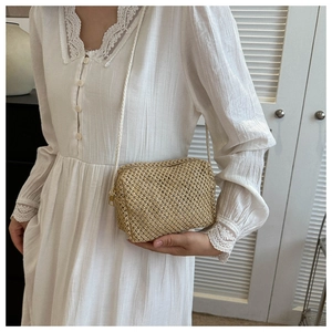 Detailed close-up of a handmade woven straw crossbody bag styled with a lace dress