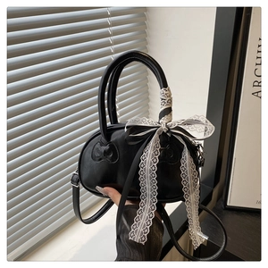Detail view of black leather mini bowling bag with white lace bow and cat charms