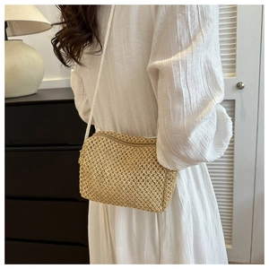 Close-up of handmade straw woven crossbody bag with metal zipper and thin white strap