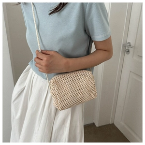 Detail of woven straw crossbody bag in beige showing fine texture and rope strap