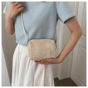 Detail of woven beige crossbody bag showing the natural texture and zipper closure