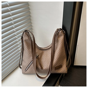 Détail du sac à bandoulière en tissu à chevrons avec sangle en cuir et étiquette