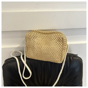 Detail shot of the woven straw texture and white rope shoulder strap on a summer crossbody bag