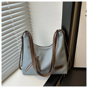 Détail du sac cabas en tissu à chevrons bleu et blanc avec poignées en cuir marron et zip