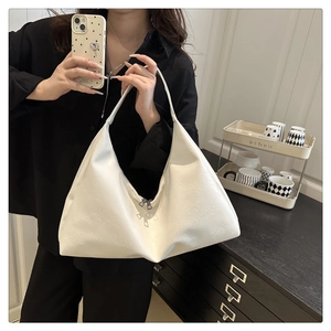 Detailed view of large white leather hobo shoulder bag with a zipper and minimalist texture
