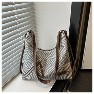Détail du sac en tissu à chevrons avec bandoulière en cuir et écusson en cuir de marque