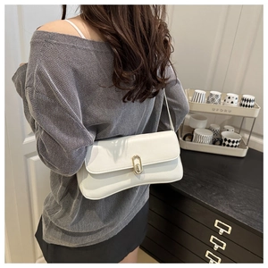 Detail view of a white leather shoulder bag with a gold oval metal lock on the flap