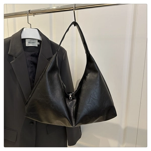 Detail shot of black wrinkled PU leather tote with metal zipper on a minimalist hanger