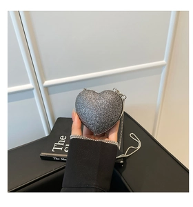 Close-up of a silver heart-shaped evening bag with sparkling sequins and chain strap