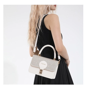 Detail of silver sequin patchwork and gold buckle on a white leather handbag
