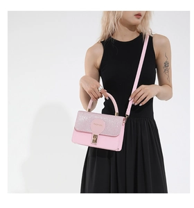 Close-up of pink crossbody bag with glitter flap and golden metal lock for women