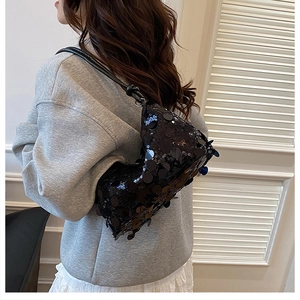 Close-up of black sequined shoulder bag with leather knotted strap and glossy texture