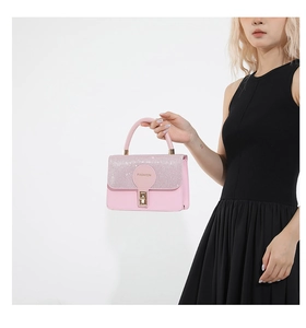 Detail of pink small square handbag featuring sequined flap and golden metal clasp