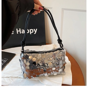 Detailed view of silver sequin handbag featuring black leather knotted strap and zipper