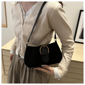 Detail of a vintage black shoulder bag featuring a classic gold horseshoe metal buckle closure