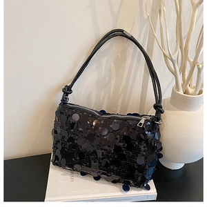 Detail view of glossy black large sequins on a trendy underarm bag for women