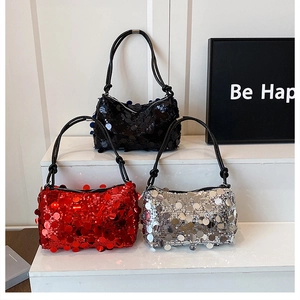 Detail view of sequined handbags in black, red, and silver with chain straps on a white podium