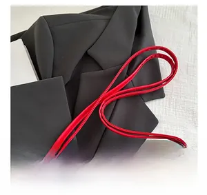 Detailansicht der roten PU-Leder-Schultertasche mit schmalem Riemen auf schwarzem Blazer