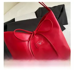 Detailansicht der roten Ledertasche mit dekorativer Schleife und silbernen Metallelementen